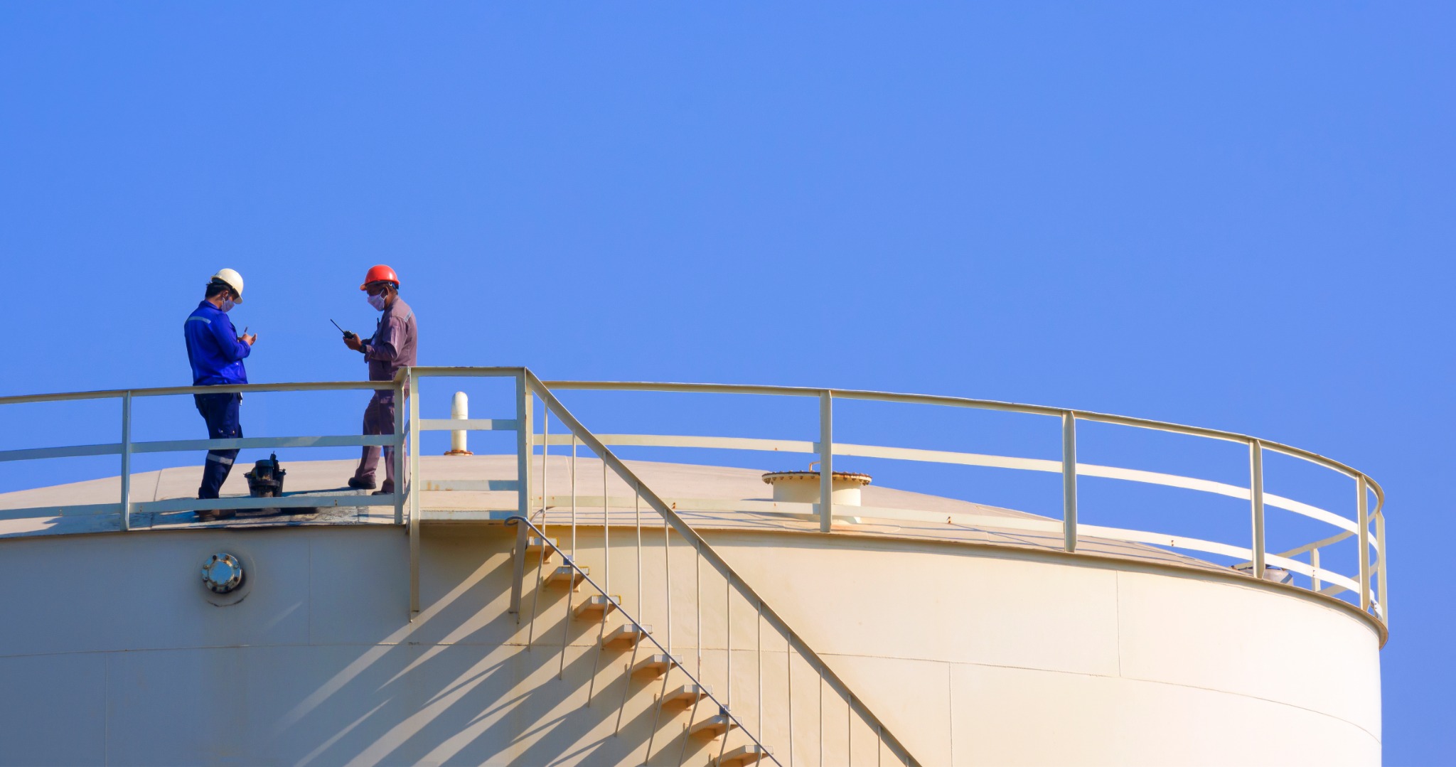 Two industrial professionals reviewing work on a storage tank